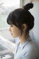 A woman looking out of a window with her hair in a bun.