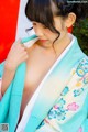 A woman in a blue and white kimono is adjusting her hair.