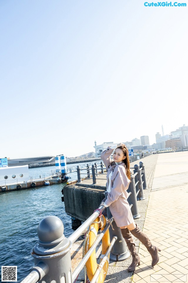 A woman standing on a pier next to the water.