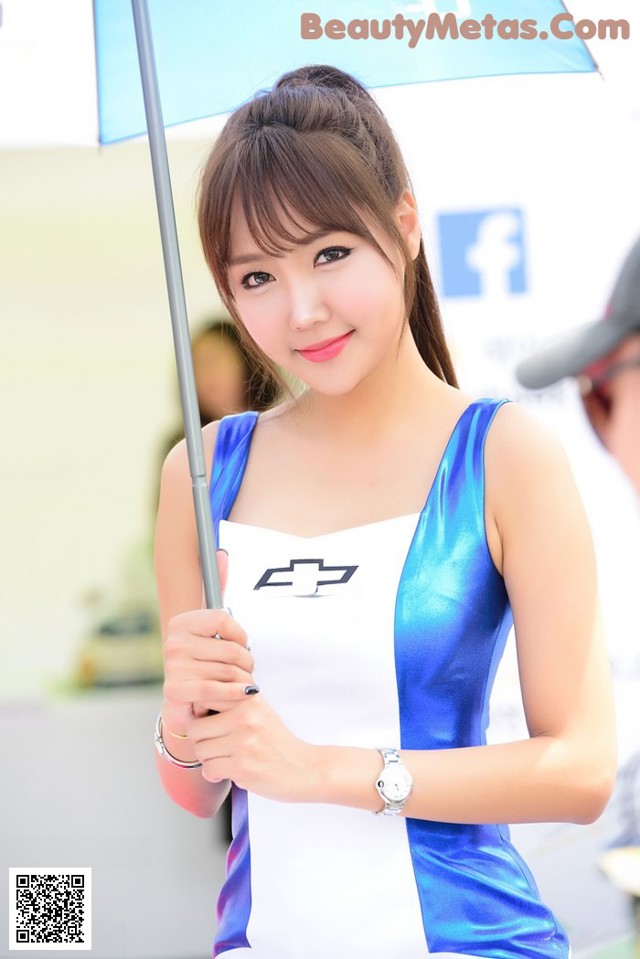 A woman in a blue and white dress holding an umbrella.