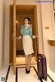 A woman standing in front of a door with a suitcase.