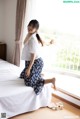 A woman sitting on a bed in a hotel room.