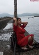 A woman in a red dress sitting on a dock.