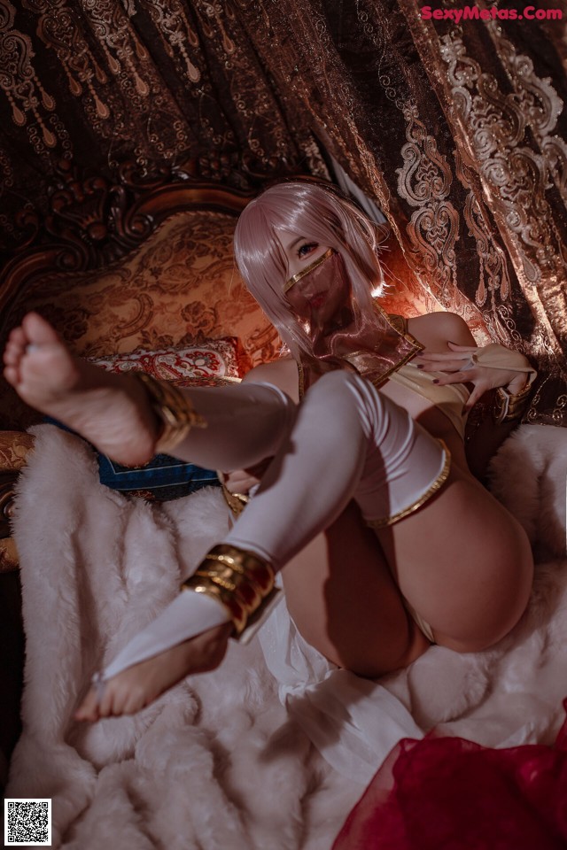 A woman in a white outfit is sitting on a bed.