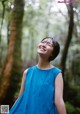 A woman in a blue dress standing in the woods.