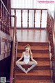 A woman sitting on the stairs of a house.