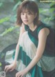 A woman in a green and white dress sitting on a rock.