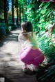 A little girl in pink leggings crouching down on a wooden walkway.