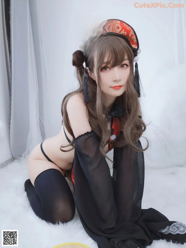 A woman in a black and red outfit sitting on a white rug.