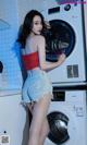 A woman standing in front of a washing machine.